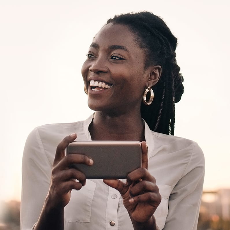 A woman holding a phone while smiling