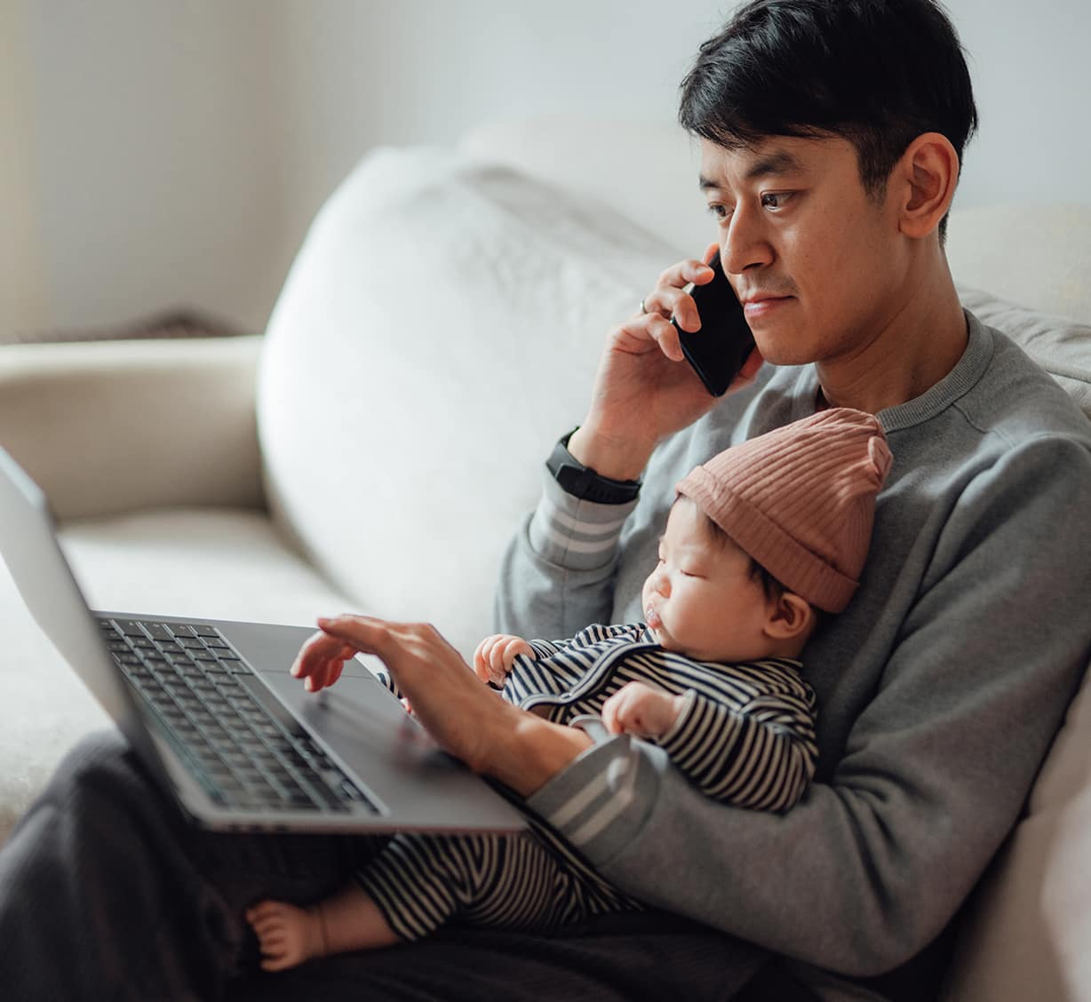 a man and baby looking at laptop and talking over phone