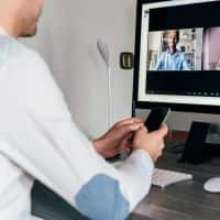 hombre con teléfono en la mano mirando la pantalla de la computadora