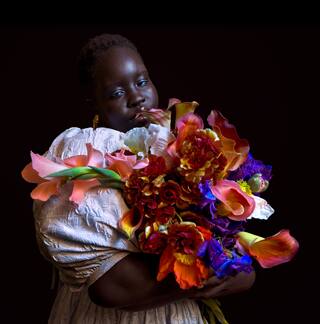 Foto con poca luz de una persona sosteniendo un ramo de flores coloridas.