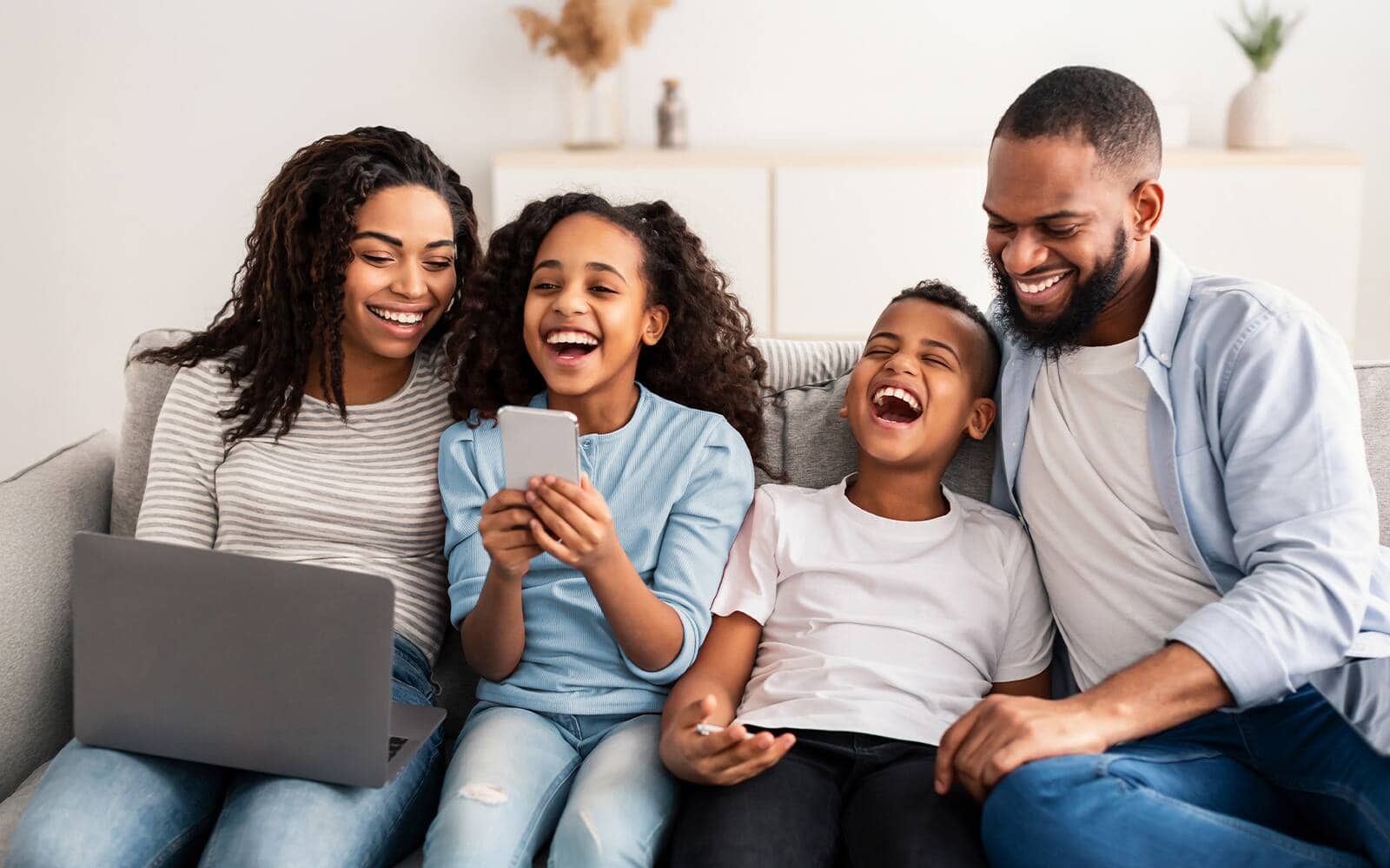A family of four sitting on the couch, laughing